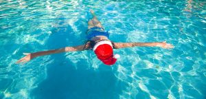 Back view of beautiful woman in santa hat on blue water image